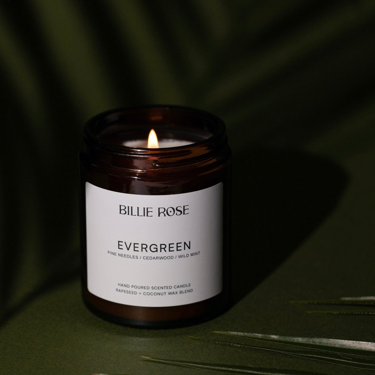 Billie Rose Evergreen candle on a dark green background