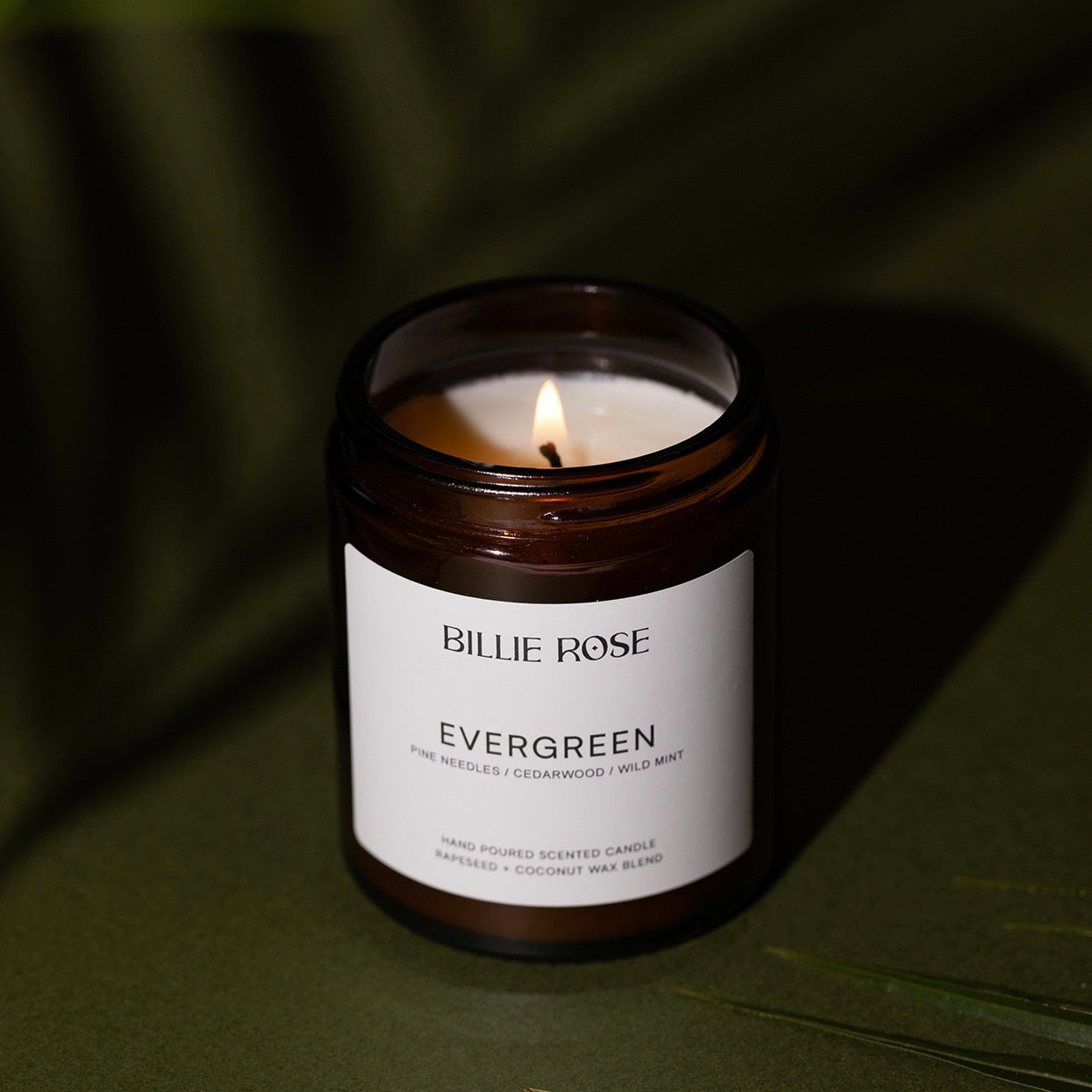 Candle in a jar labeled 'Evergreen' by Billie Rose on a dark background