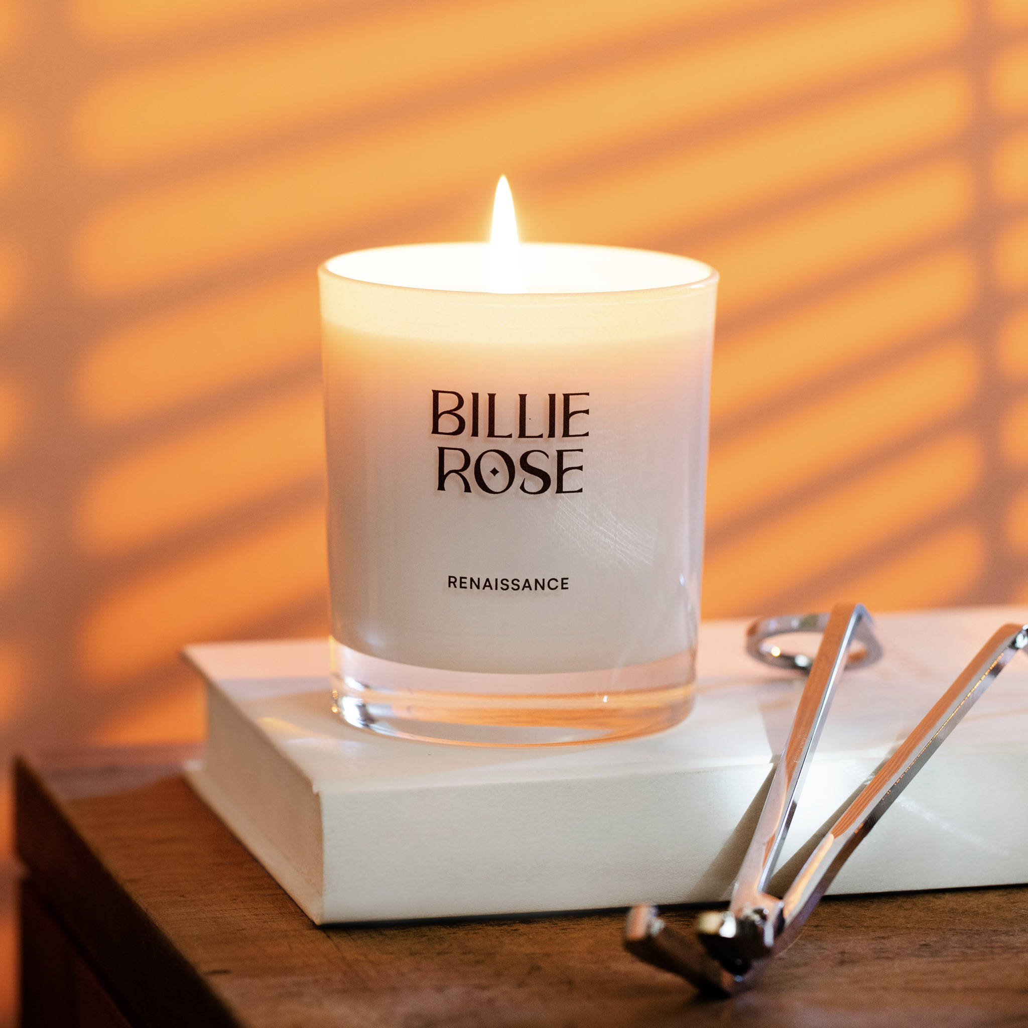 Billie Rose candle on a book with a warm glow