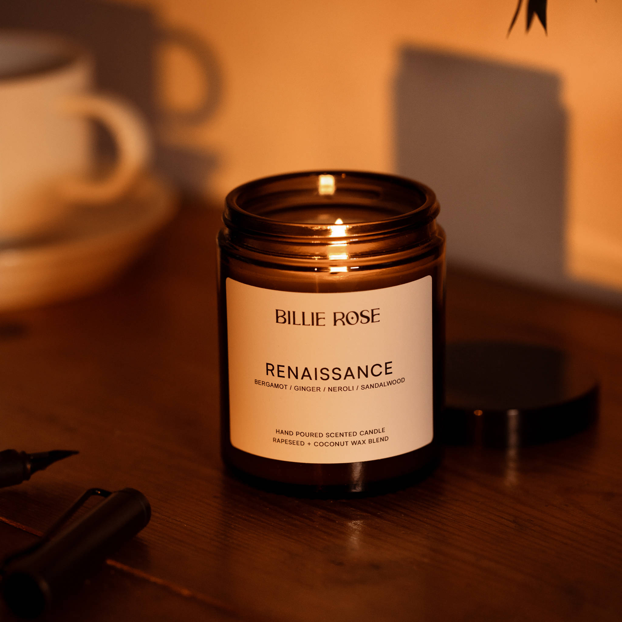 Billie Rose Renaissance candle on a wooden surface with a cup and pen in the background