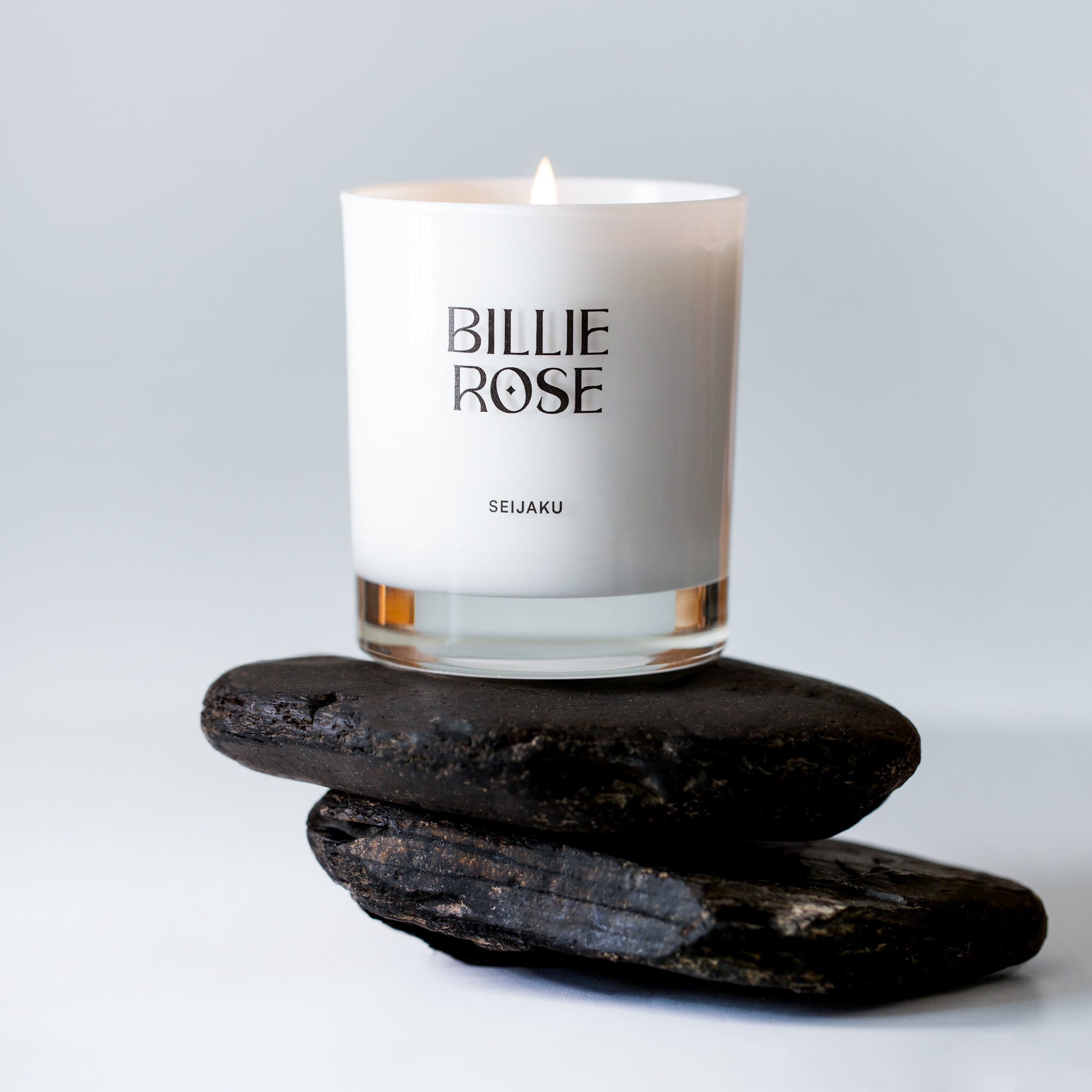 Seijaku candle in white jar sitting on pebbles