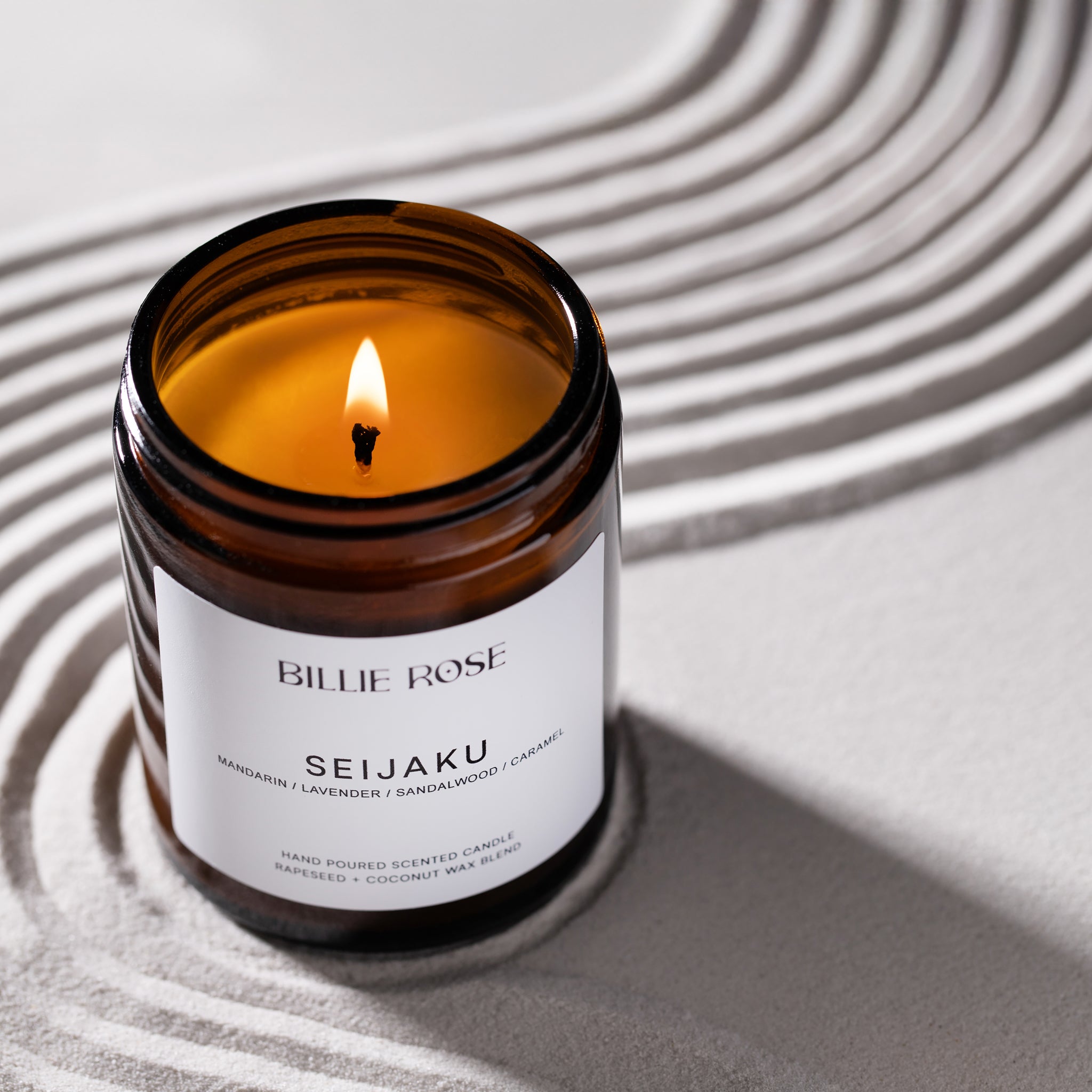 lit scented candle on zen raked sand background