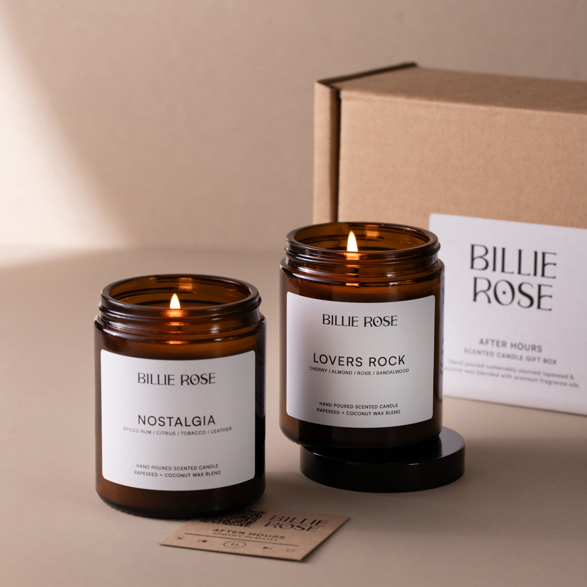 Two lit candles from Billie Rose with their packaging on a beige background