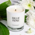 lit candle in white glass surrounded by flowers