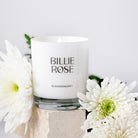 White candle with 'Billie Rose' branding surrounded by white flowers on a light background