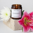 lit floral scented candle on concrete block with white and pink flowers
