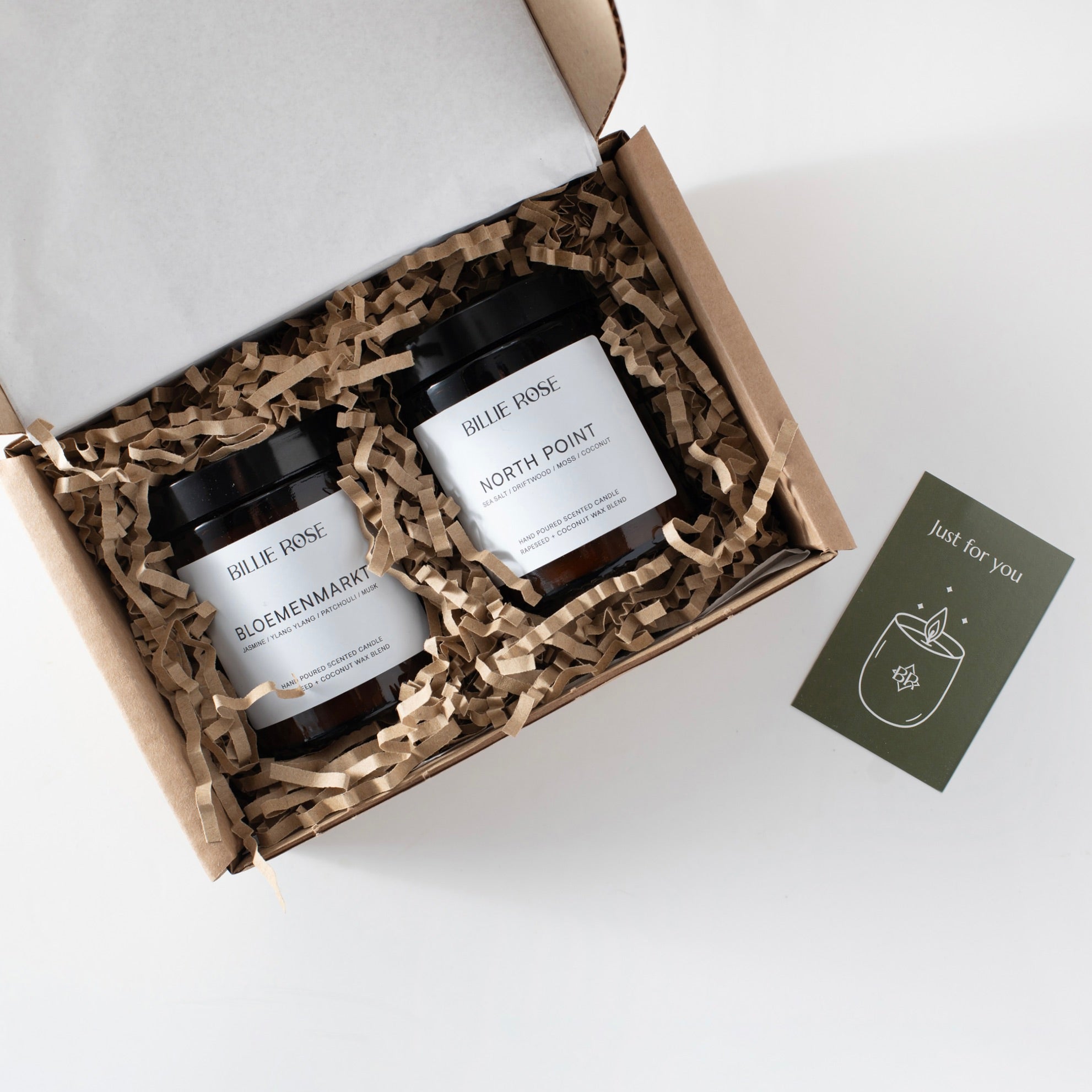 Two candles in a gift box with a card on a white background
