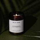 Billie Rose Evergreen candle on a dark green background