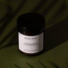amber jar candle with lid on green background with tree shadows