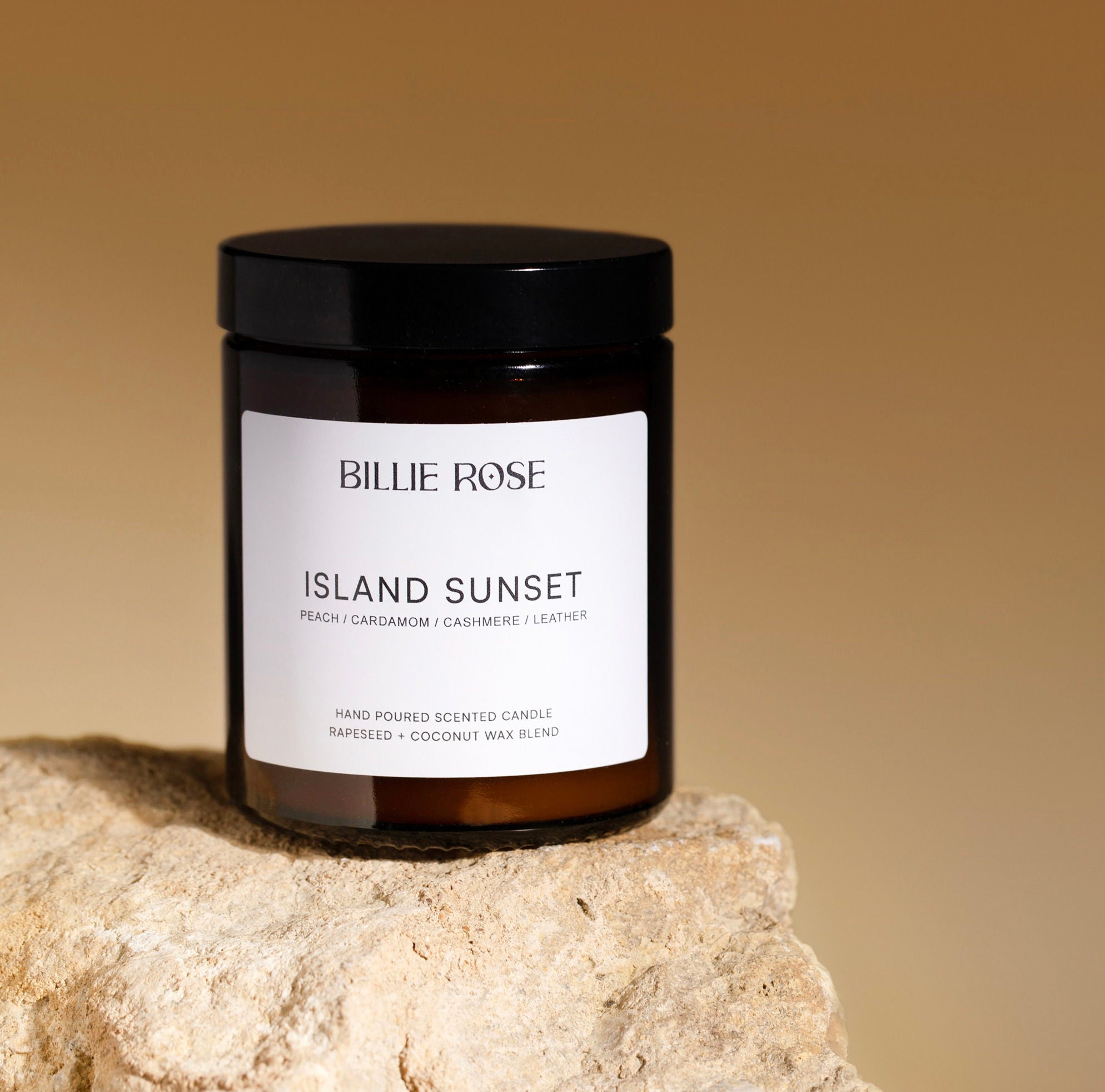 Candle jar labelled 'Island Sunset' by Billie Rose on a stone surface with a warm background
