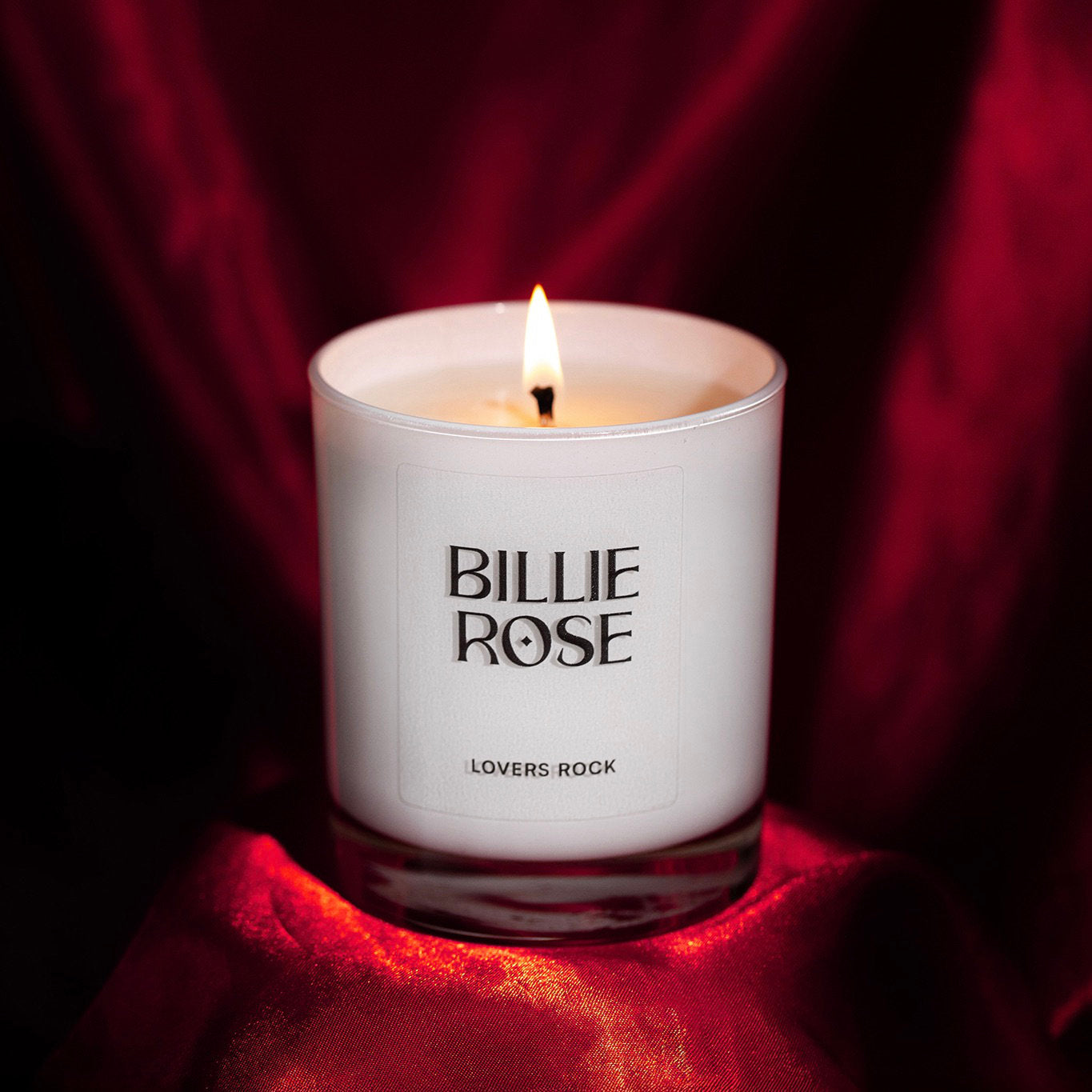 Candle in a 'Billie Rose' container on a red fabric background