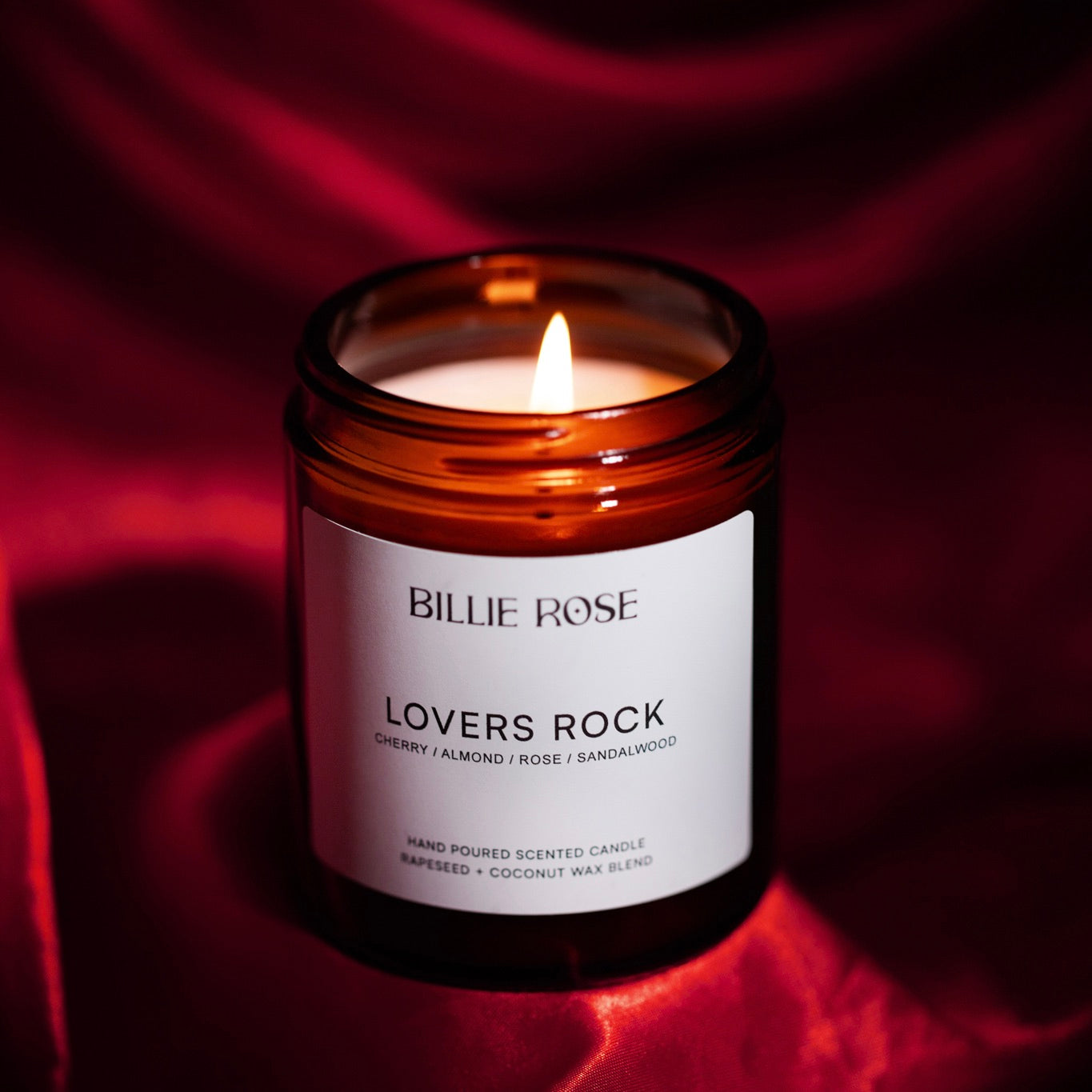 Lit scented candle on red background