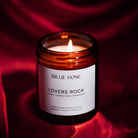 Lit scented candle on red background