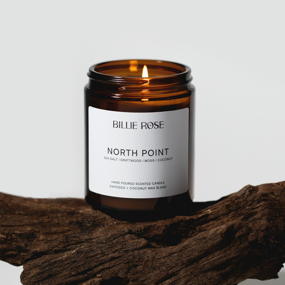 Billie Rose North Point candle in amber jar on a wooden surface with a white background