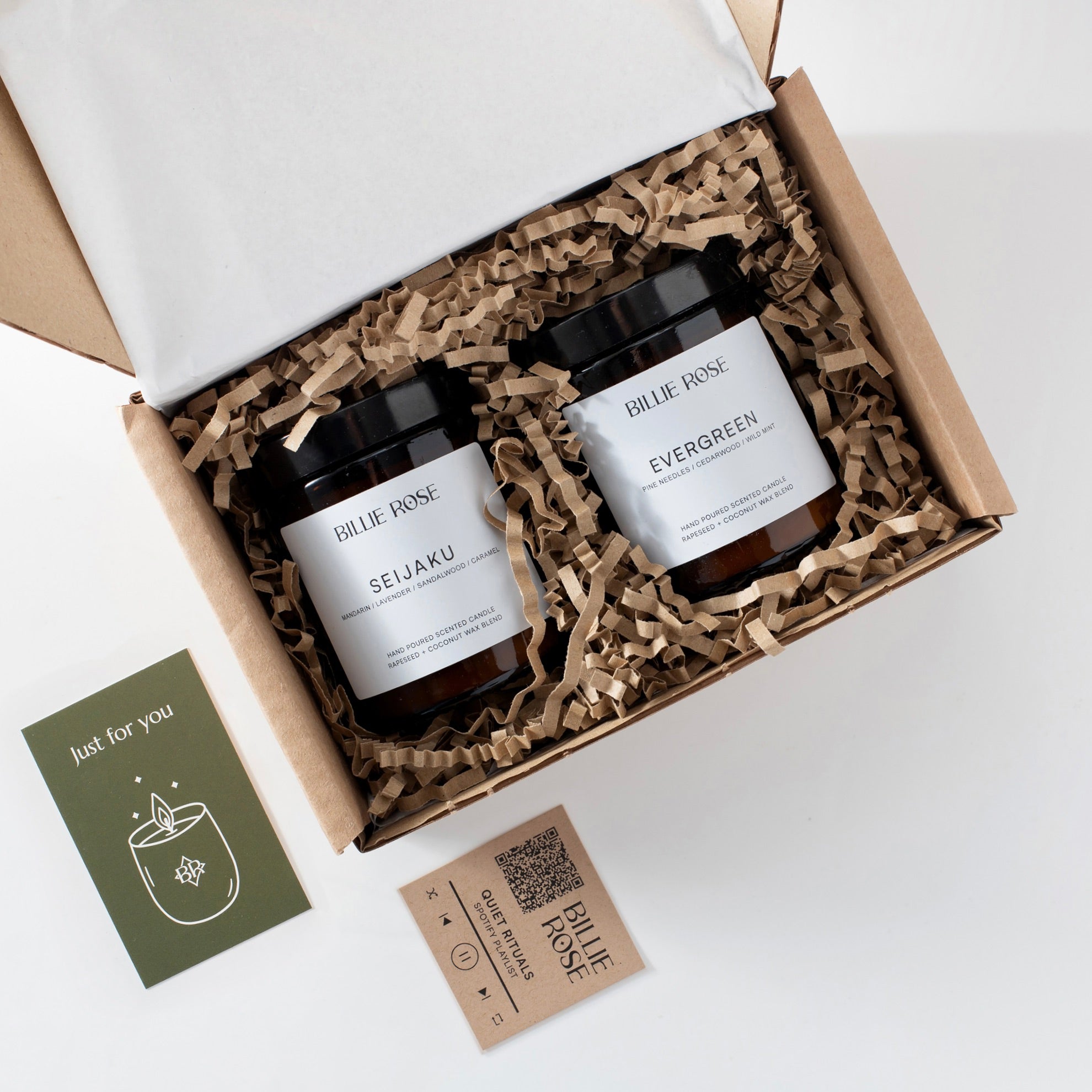 Two candles in a gift box with a gift card and playlist card on a white background