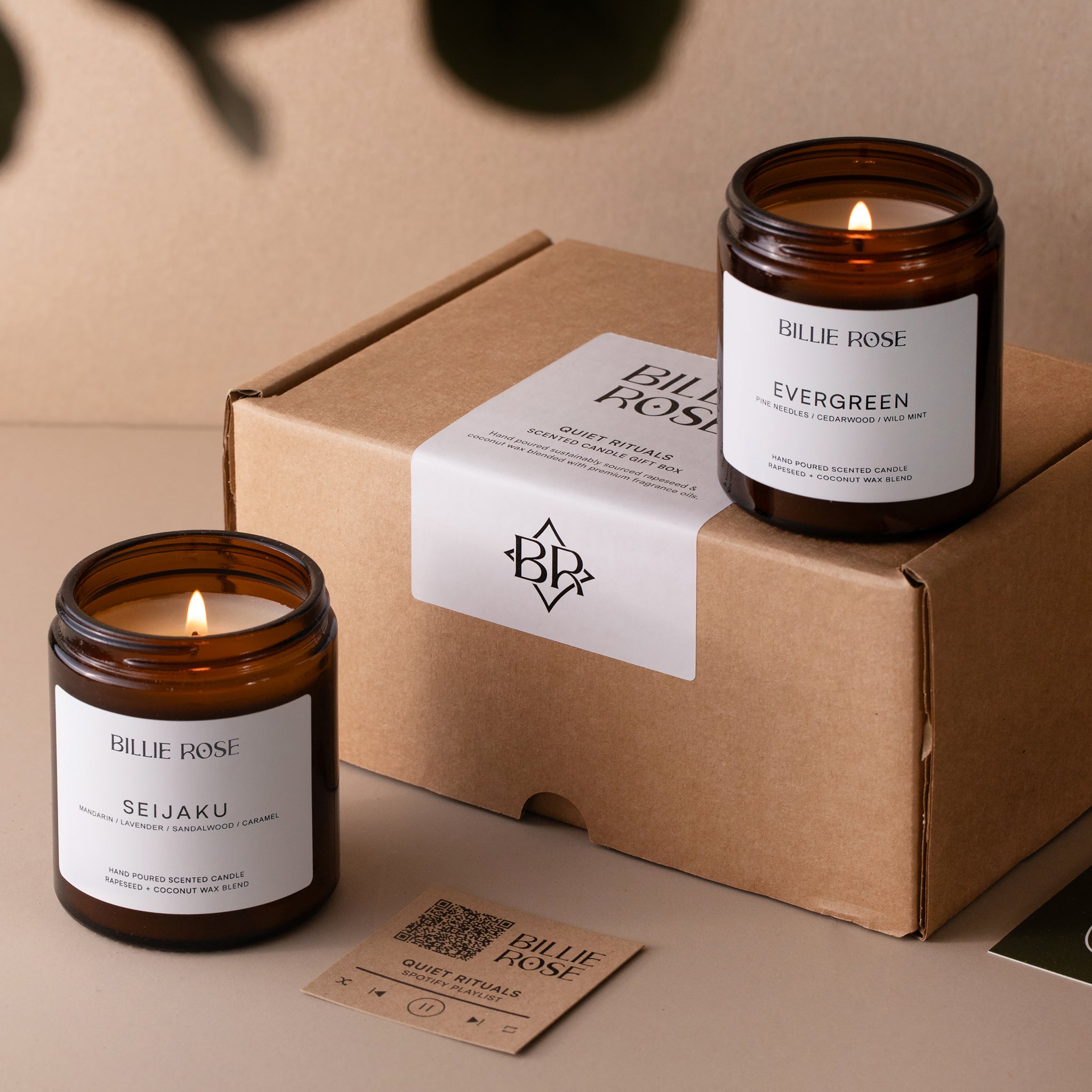 Two lit candles with 'Billie Rose' branding on a kraft cardboard box.