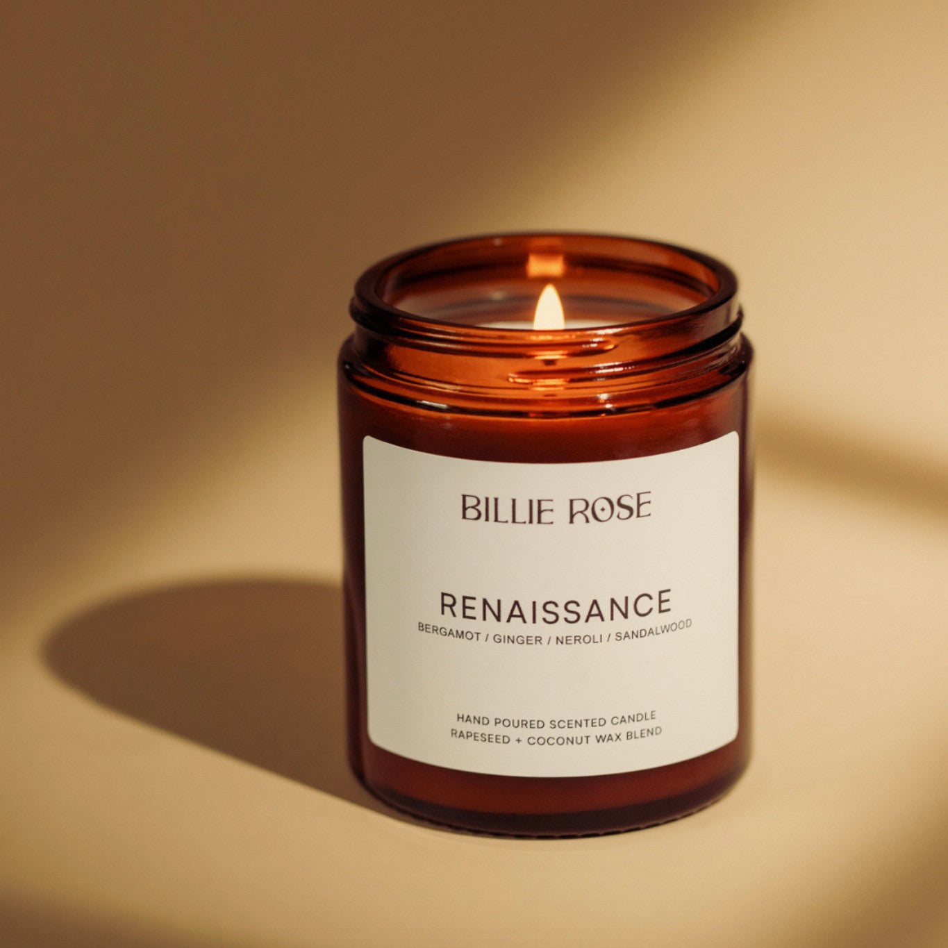 Scented candle in an amber jar with a label on a beige background