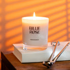 Billie Rose candle on a book with a warm glow