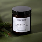 Candle jar labeled 'Billie Rose Wild Earth' on a green background with a pine branch.