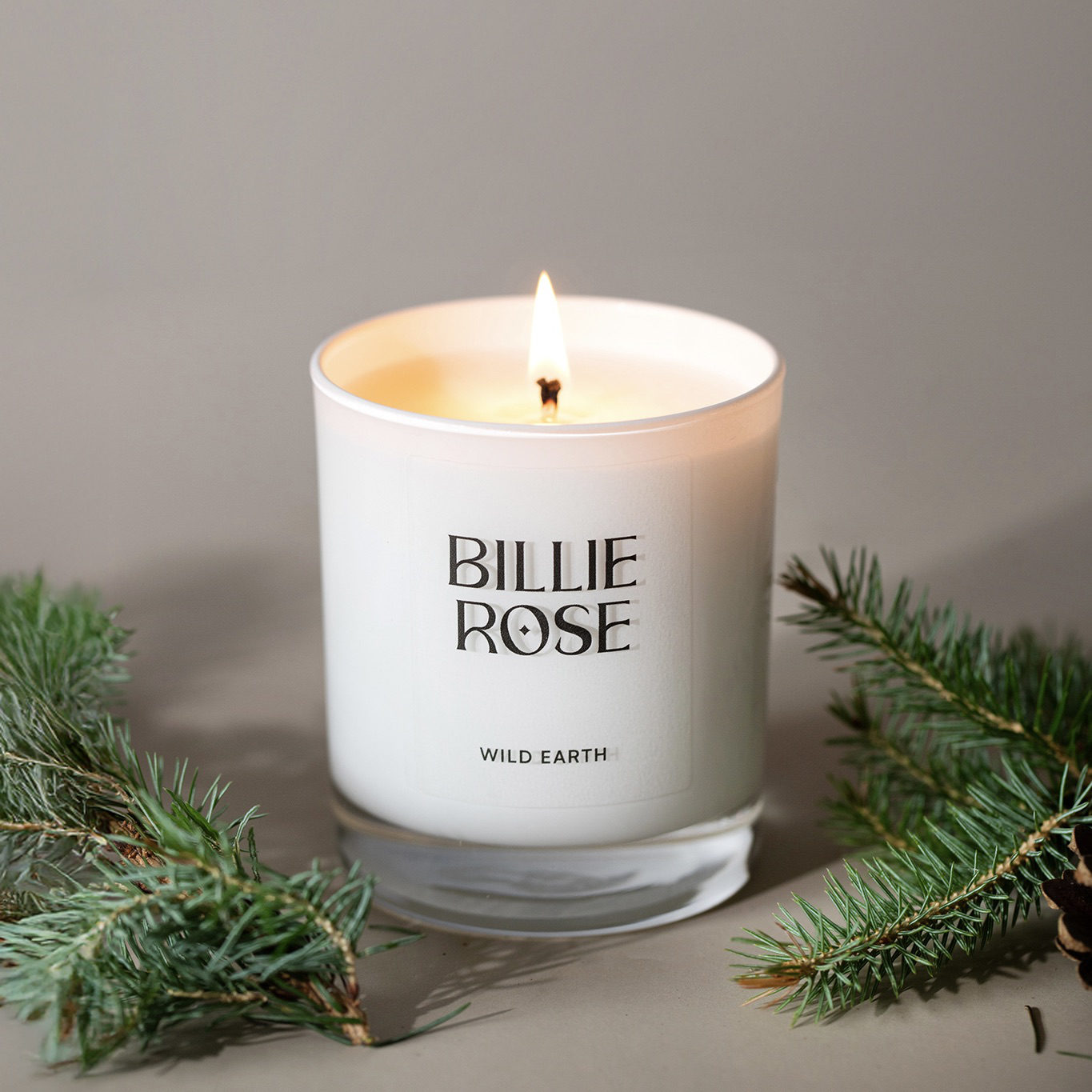 Billie Rose candle with greenery on a neutral background