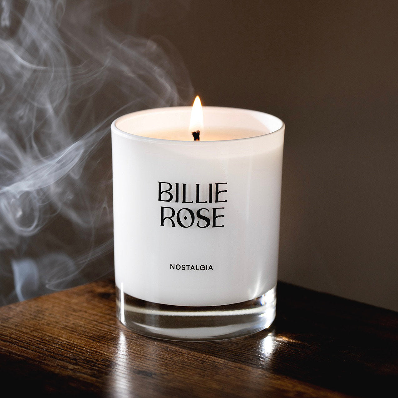 lit candle on brown background with smoke billowing at the side